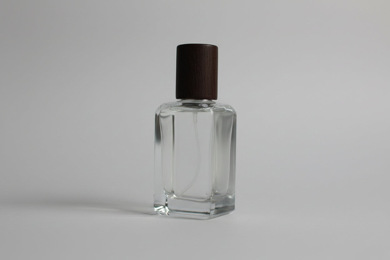 Clear nail polish bottle with brown cap on a white surface