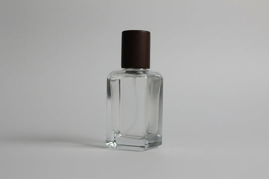 Clear nail polish bottle with brown cap on a white surface